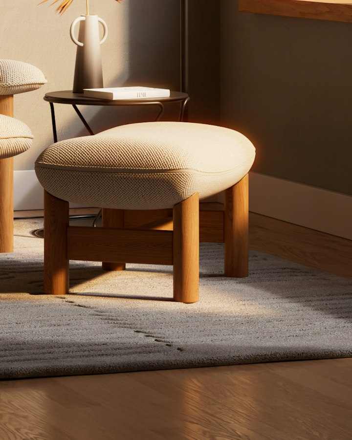 Ren ottoman, a padded bouclé footstool on oak legs, on a grey wool rug