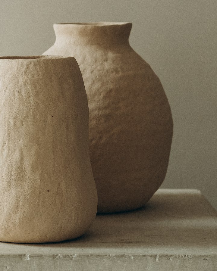 Two hand-built Sora stoneware vessels in raw sand clay on a plaster plinth