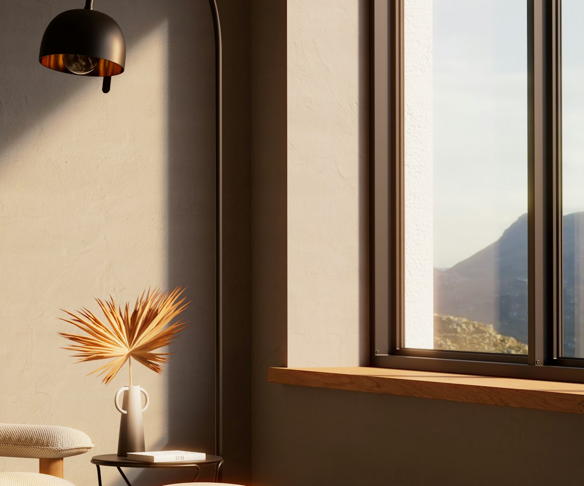 A plaster-walled corner with a tall window, a wide oak sill and late sun falling across the wall