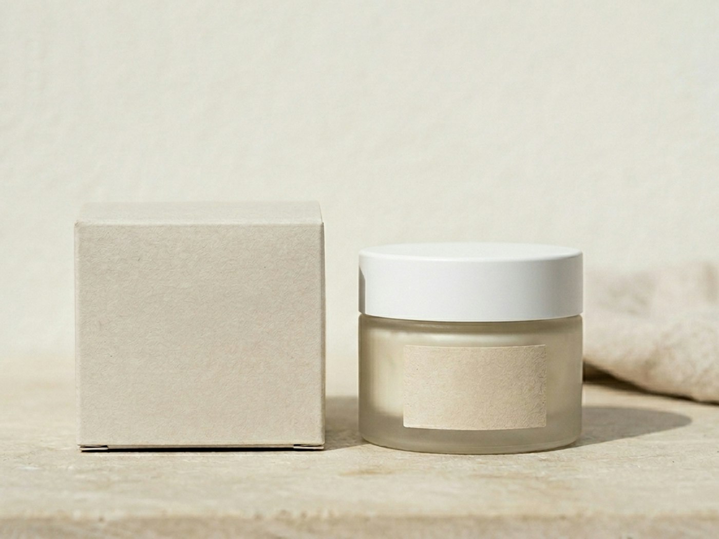 A plain kraft refill box beside a frosted glass jar with a white lid, on a travertine ledge